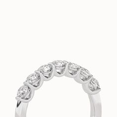 a white gold ring with five pear shaped diamonds on the sides and four rows of round brilliant