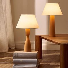 two wooden lamps sitting next to each other on top of a hard wood flooring