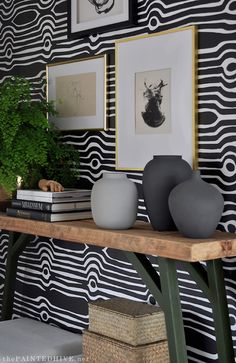 a table with two vases on top of it next to a plant and pictures