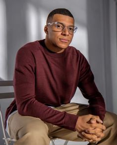 a man wearing glasses sitting in a chair