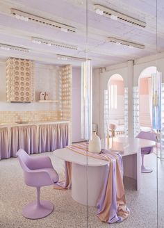 a dining room with purple chairs and a white table in front of a mirrored wall