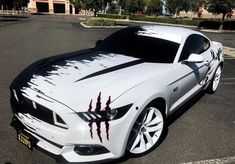 a white sports car with red paint on it's hood is parked in a parking lot