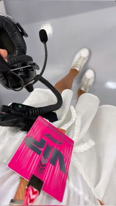 a pink sign sitting on top of a bed next to a pair of black shoes