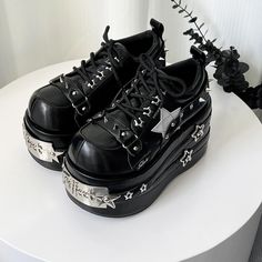 a pair of black shoes with silver stars on them sitting on top of a white table