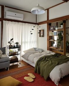 a bedroom with a bed, couch and bookshelf next to a wall mounted air conditioner