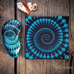 a blue and black painting sitting on top of a wooden table next to shoes, seashells and shells