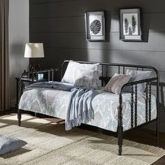 a metal daybed sitting on top of a wooden floor next to a lamp and window