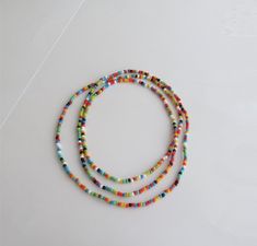 multicolored beaded bracelets are arranged on a white surface with a string attached to them