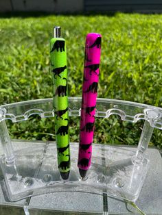 two pens sitting on top of a plastic container in the grass next to each other