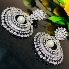 These are a beautiful pair of Earrings made with American diamonds. These chandbali work well with everything and are made with a gold base. They have white American diamond stones and White semi-precious stones in a diamond pattern that will go well with every outfit in your closet. Best for gifting or for personal use, wear it to any occasion and be the spotlight. Eye-catching and unique jewelry that will set you apart. Gift this piece to a loved one, and see their face light up with joy. Elegant Hand Set Chandbali Hoop Earrings, Elegant Chandbali Hoop Earrings Hand Set, Festive Silver Jhumkas With Elegant Design, Elegant Hand Set Round Danglers, Cubic Zirconia Round Danglers With Matching Earrings, Elegant Silver Chandbali Hoop Earrings, Silver Diamond Jhumkas With Intricate Design, Silver Chandbali Hoop Earrings, Elegant Chandbali Silver Hoop Earrings