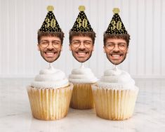 three cupcakes with one man's face wearing a birthday hat and the other has glasses