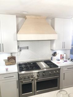 a stove top oven sitting inside of a kitchen next to white cabinets and counter tops