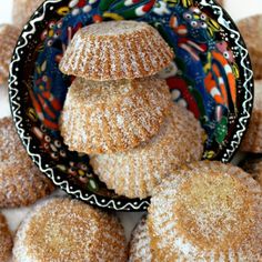 powdered sugar cookies stacked on top of each other in front of a plate full of them