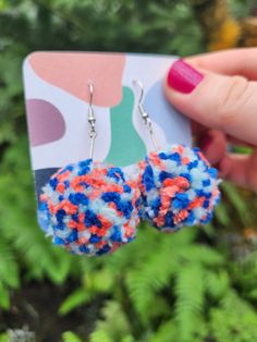 a pair of red, white and blue pompom earrings