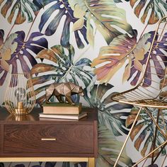 a tropical wallpaper with palm leaves on it and a gold chair next to it