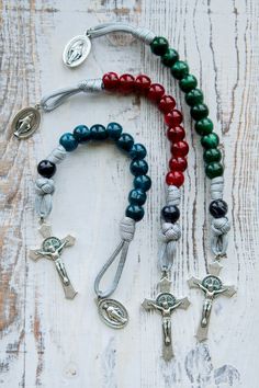 Embrace the power of prayer with our Gemstone Colored - 1 Decade Paracord Rosary, the perfect spiritual weapon for adults or children alike to conquer life's battles. This single decade rosary is designed to be your constant companion, ensuring you never leave your spiritual armor behind.Our Gemstone Colored - 1 Decade Paracord Rosary features a grey paracord rope, adorned with gemstone colored Hail Mary beads and a normal-sized St. Benedict Crucifix. The devotional medal of this design is the M God Bracelet, Decades Of The Rosary, Rosary Making, Paracord Rope, Spiritual Armor, Paracord Rosary, Blue And Magenta, Rosary Jewelry, Rosary Prayer