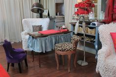 a living room filled with lots of furniture next to a window covered in red and white curtains