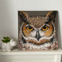 an owl painting on a shelf next to a vase