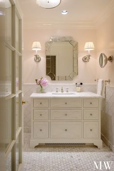 a bathroom with two sinks and a large mirror above the sink is lit by three lights