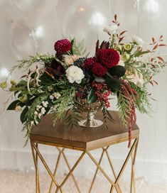 an arrangement of flowers is sitting on a small table