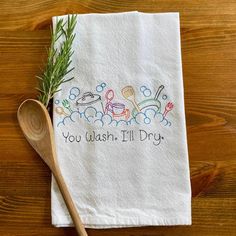 an embroidered dish towel with the words you wash i'll dry on it next to a wooden spoon