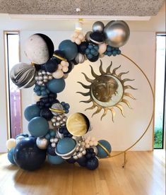 a sun and moon balloon arch in a room with wooden floors, white walls and wood flooring