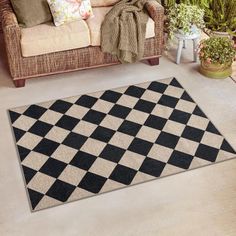 a black and white checkered rug on the floor in front of a couch with pillows