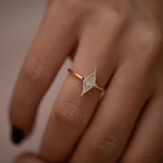 a woman's hand with a diamond ring on top of her finger and the other hand holding it