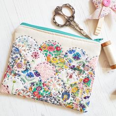 a small zippered pouch is decorated with colorful flowers and has a pair of scissors next to it