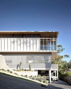 an architecturally designed house on the side of a hill with a car parked in front