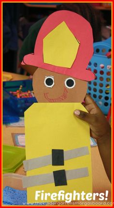 a fireman paper doll holding up a piece of paper with the word firefighter on it