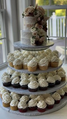 three tiered wedding cake with cupcakes on top