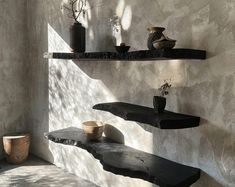 some shelves with vases and bowls on them in a room that has concrete walls