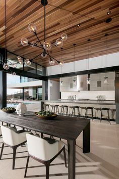 the dining room table is surrounded by white chairs and wooden ceiling lights that hang from the rafters