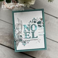 a close up of a card on a table with flowers in the foreground and an image of a snowflake