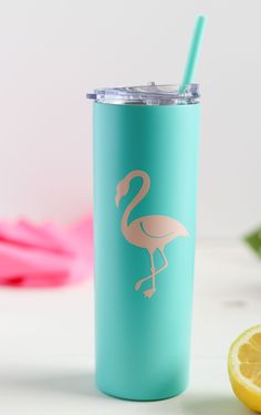 a blue tumbler with a pink flamingo on it next to a lemon slice