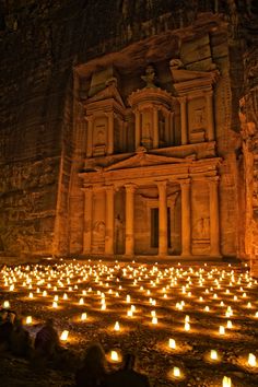 many lit candles are placed in front of an ancient building