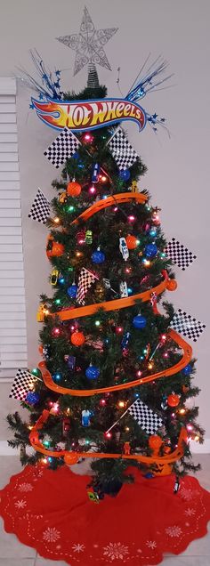 a decorated christmas tree in the corner of a room with an orange ribbon around it