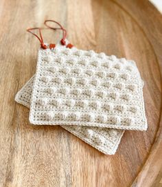 two crocheted dishcloths sitting on top of a wooden table next to each other