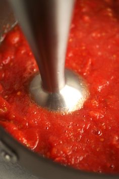 a sauce being stirred in a pot with a metal spoon