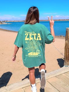 a woman walking down a wooden walkway towards the ocean with her hand in the air