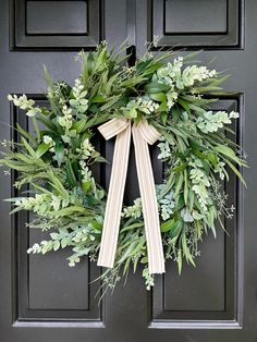 a wreath on the front door is adorned with greenery and ribbon for an elegant touch