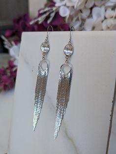 Fancy up your Friday date night or your casual weekend t-shirt with these long rhodium-plated tassel earrings.  You'll surely dazzle with these unique showstopping boho-style shimmering tassel fringe earrings. These beautiful earrings, with their herringbone pattern, are a testament to our commitment to quality. They dangle from silver-plated ear wires and a silver-plated oval shaped cubic zirconia connector, ensuring their durability and long-lasting beauty. The earrings are hung from silver-plated sloped ear wires. The base metal is brass, nickel-free, and lead-free. The ear wires are hammered with smooth ends and 21 gauge. They measure 25mm X 10mm. Sterling Silver ear wires are available for an additional $5.00 fee. Please message me. Adjustable Silver Tassel Earrings For Party, Silver Tassel Earrings With Fringe As Gift, Silver Fringe Chandelier Drop Earrings, Silver Fringe Drop Earrings, Silver Fringe Long Drop Earrings, Trendy Silver Dangle Tassel Earrings, Trendy Silver Tassel Drop Earrings, Earrings Long Silver, Long Silver Earrings