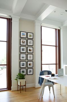 a living room filled with lots of windows next to a white table and chair on top of a hard wood floor