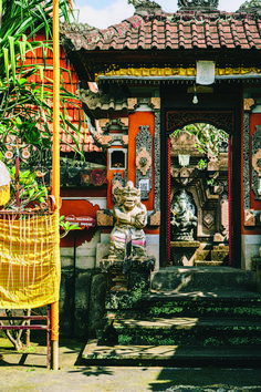 a statue sitting in front of a red and yellow building