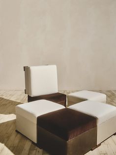 a white and brown couch sitting on top of a wooden floor next to a wall