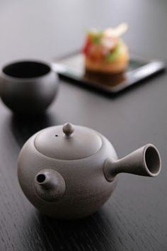 the teapot is sitting on the table next to two small cups and a plate