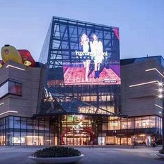 the entrance to a shopping center with large billboards on it's sides and lights