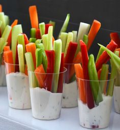 small cups filled with different types of veggies on top of a white table