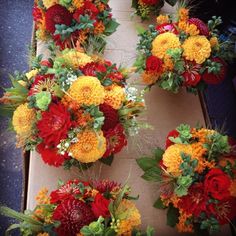 several bouquets of flowers are arranged on a table top, with leaves and foliage